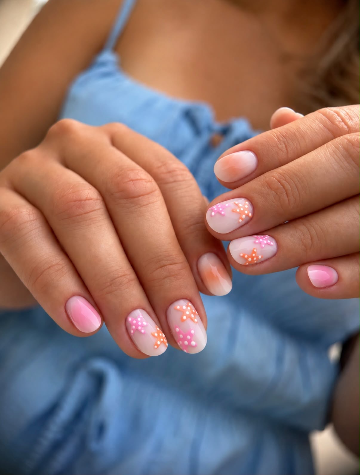 Manucure rose et orange avec motifs floraux délicats